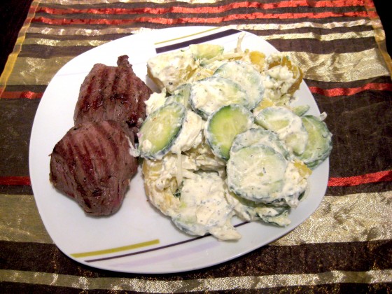 Rosarot gebratenes Steak, serviert mit cremigem Kartoffel-Gurkensalat, verfeinert mit Oregano und Petersilie